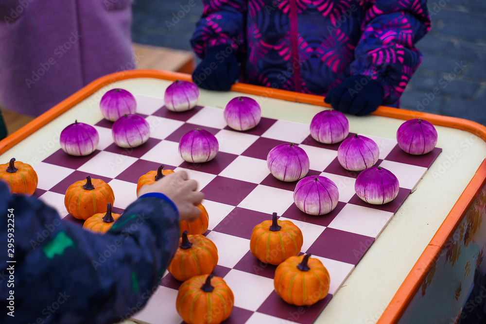 Chess Board with Pumpkins. Close up of checkered board with pumpkin checkers, colorful background 