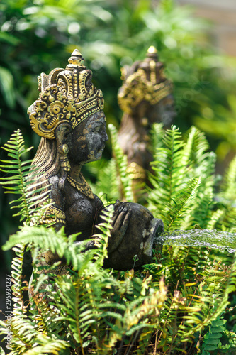 Balinese statuette of a girl with a pot from which water flows. Pool decoration