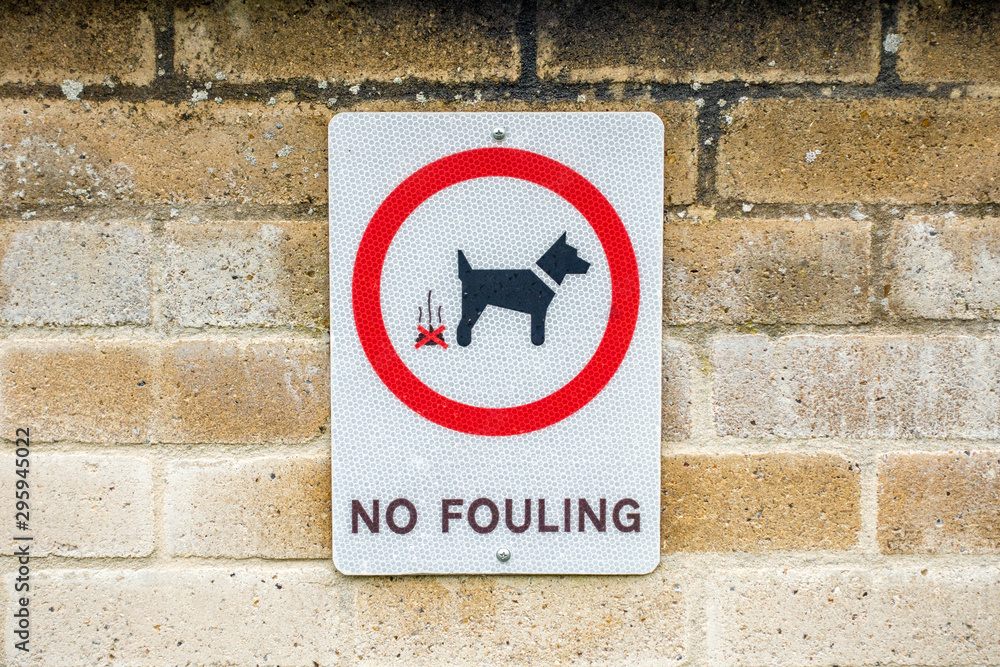 A sign on a brick wall warning dog owners not to allow their pets to foul the area. A sign on a brick wall warning dog owners not to allow their pets to foul the area.