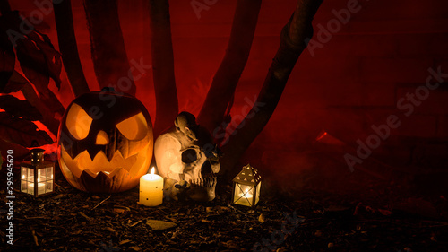 Halloween Pumpkin and skull surrounded by dark trees and red smoke