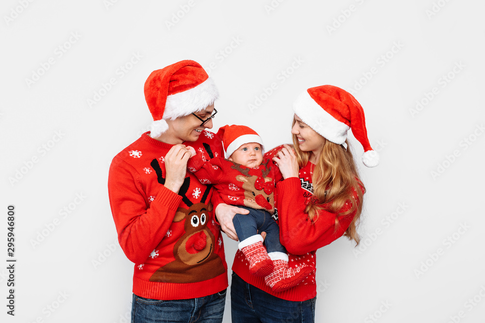 Obraz premium Happy family in Santa hats, mom dad and little baby celebrate Christmas