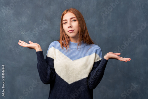 Young girl in warm blue sweater isolated on wall.