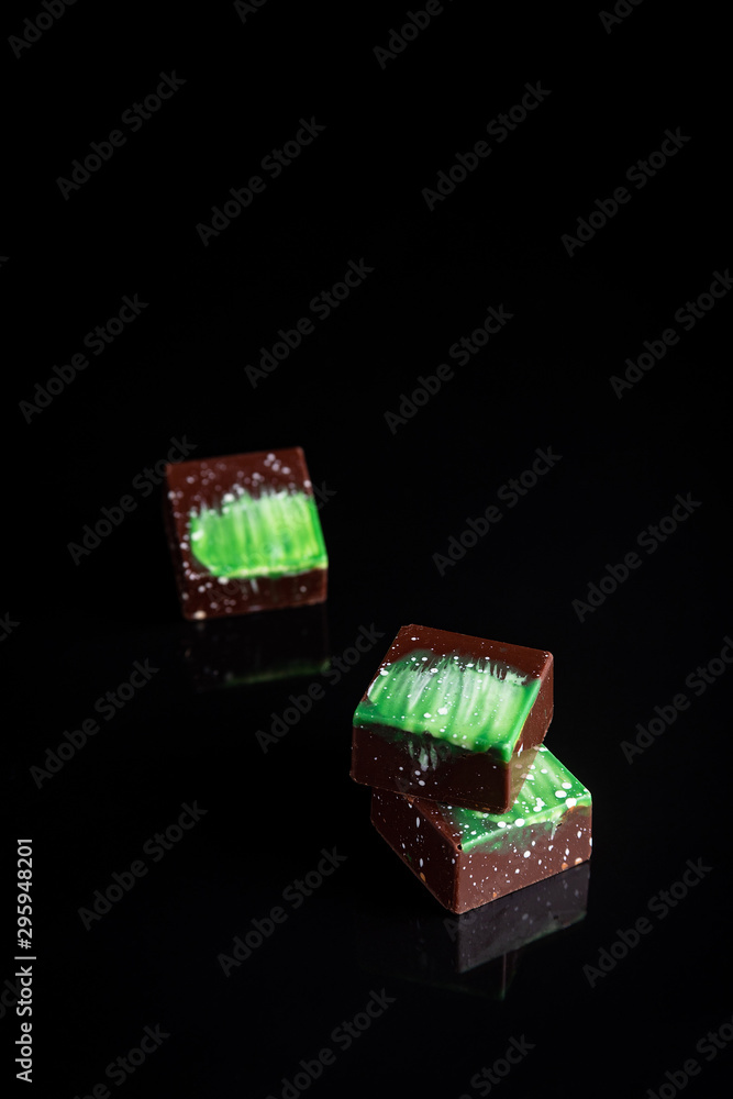 Obraz premium Art colorful chocolate candies on black background, selected focus