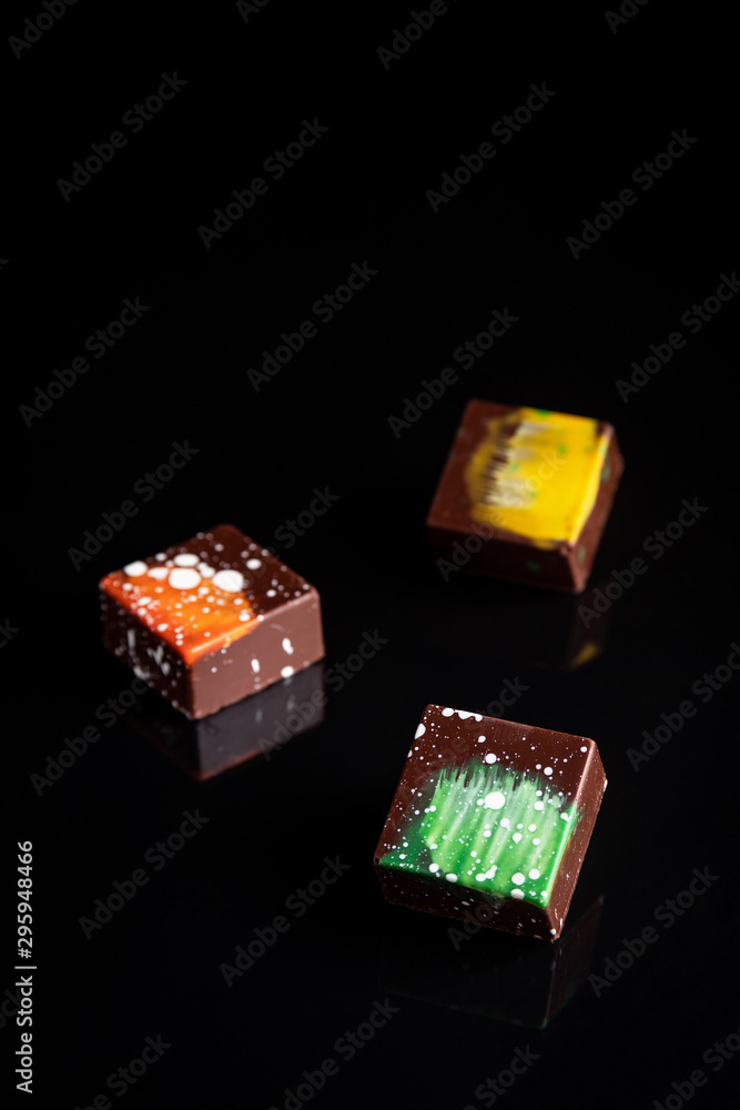 Obraz premium Art colorful chocolate candies on black background, selected focus