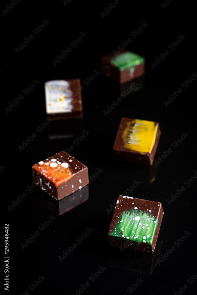 Obraz premium Art colorful chocolate candies on black background, selected focus