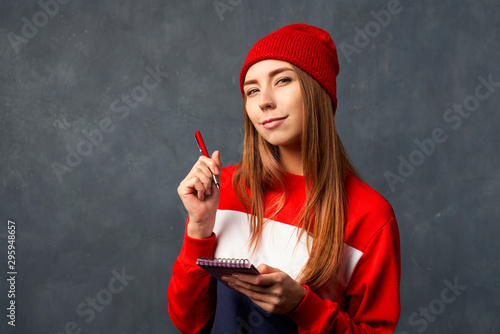 girl holds notepad, pen isolated on textured wall