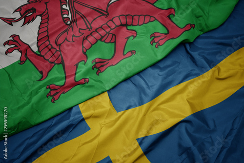 waving colorful flag of sweden and national flag of wales.