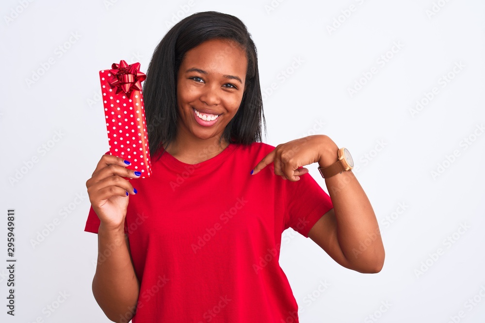 Young african american woman holding birthday present over isolated background with surprise face pointing finger to himself Young african american woman holding birthday present over isolated background with surprise face pointing finger to himself