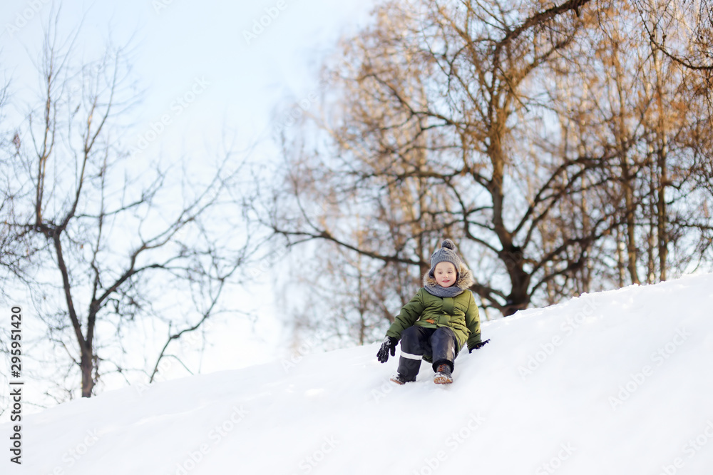 Little boy enjoying riding on ice slide in winter.