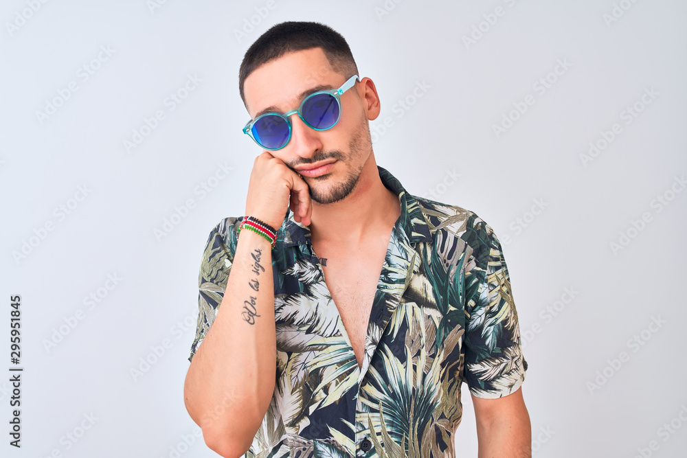 Young handsome man wearing Hawaiian sumer shirt and blue sunglasses over isolated background thinking looking tired and bored with depression problems with crossed arms.