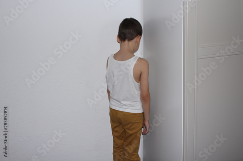 punished for a bad deed the boy stands in the corner, his back, educational concept photo