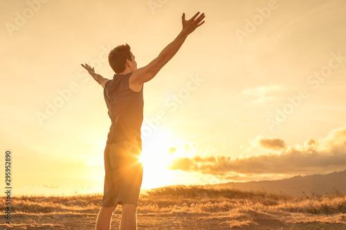 Fototapeta Szczęśliwy mężczyzna patrzeje do nieba z rękami podnosić do zmierzchu.
