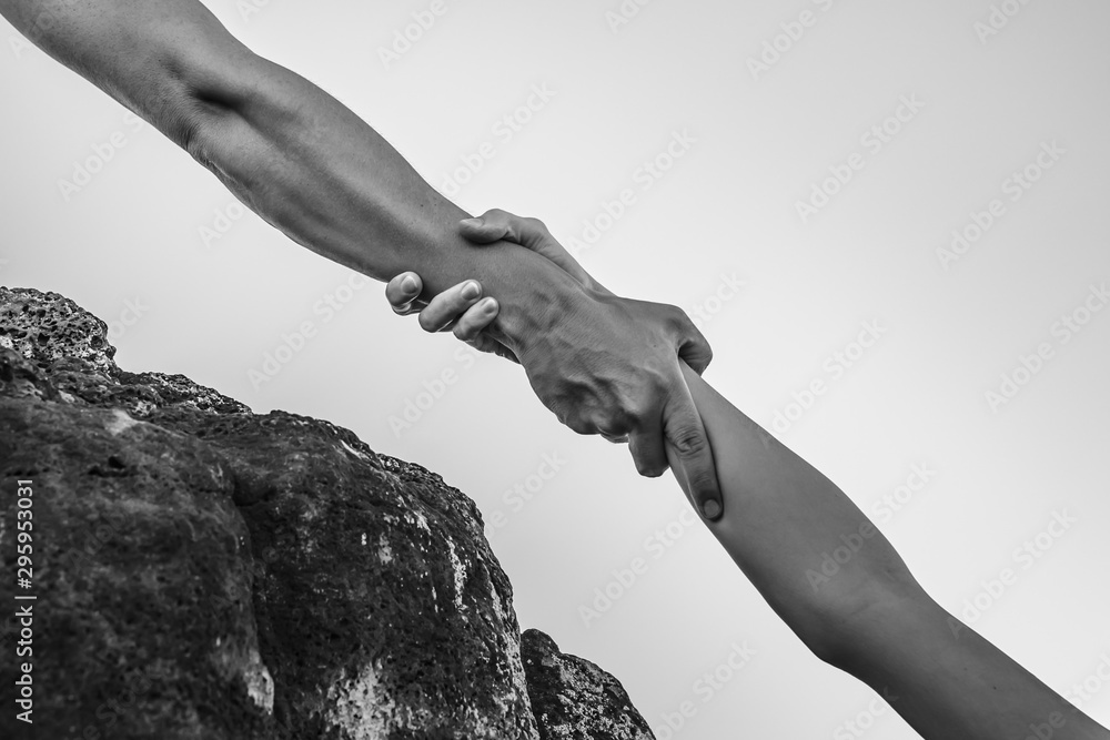Person pulling friend up edge of cliff. Helping a friend in need. Stock