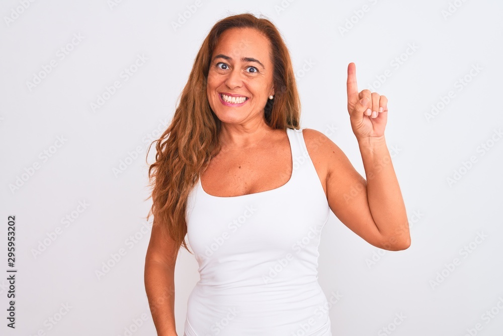 Middle age mature woman standing over white isolated background showing and pointing up with finger number one while smiling confident and happy. Middle age mature woman standing over white isolated background showing and pointing up with finger number one while smiling confident and happy.