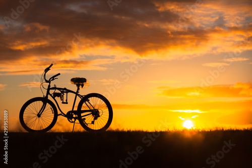 Silhouette of bicycle on field at sunset.  