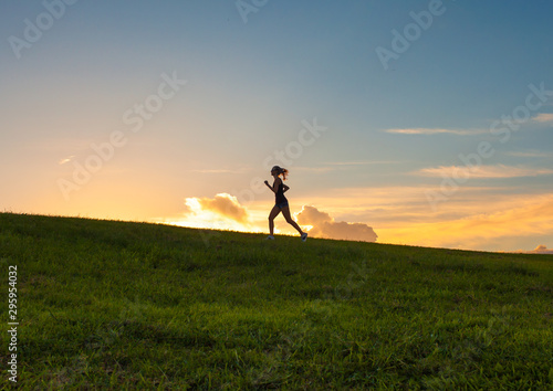 Female running up hill at sunset. 