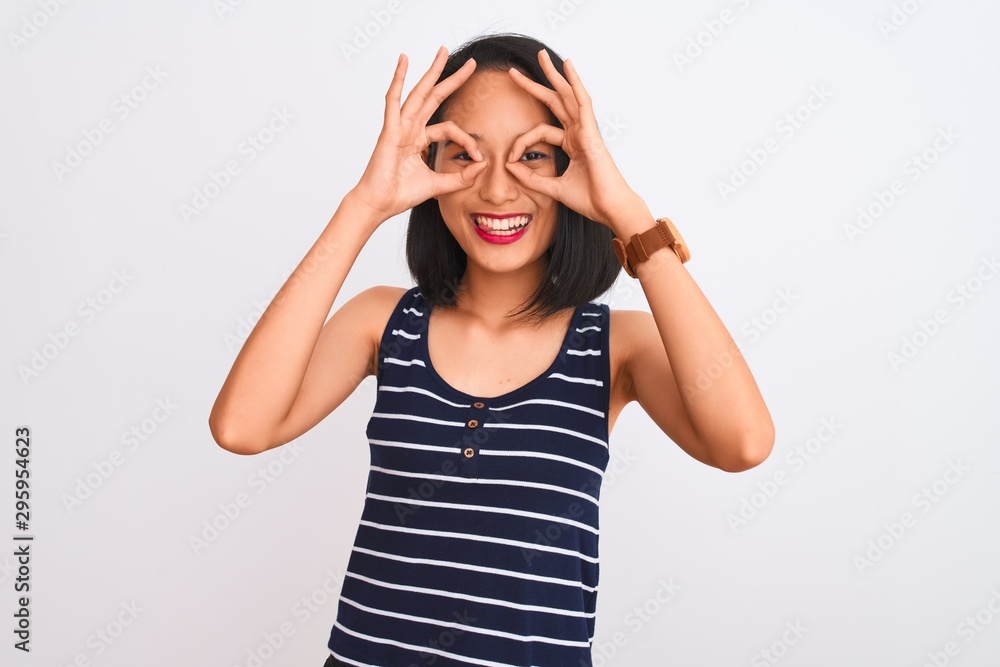 Young chinese woman wearing striped t-shirt standing over isolated white background doing ok gesture like binoculars sticking tongue out, eyes looking through fingers. Crazy expression. Young chinese woman wearing striped t-shirt standing over isolated white background doing ok gesture like binoculars sticking tongue out, eyes looking through fingers. Crazy expression.