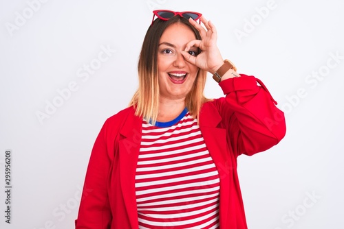 Young beautiful woman wearing striped t-shirt and jacket over isolated white background doing ok gesture with hand smiling, eye looking through fingers with happy face.