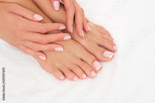 Perfectly done manicure and pedicure on female feet isolated on white background.