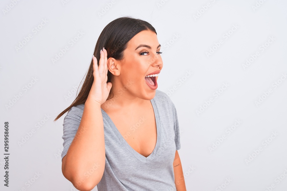 Portrait of beautiful young woman standing over isolated white background smiling with hand over ear listening an hearing to rumor or gossip. Deafness concept. Portrait of beautiful young woman standing over isolated white background smiling with hand over ear listening an hearing to rumor or gossip. Deafness concept.