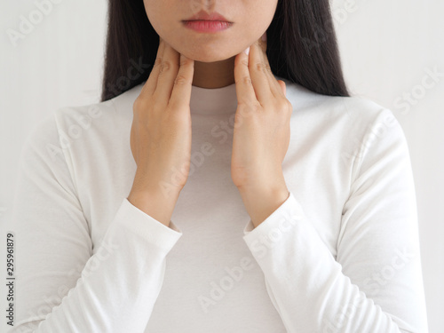 thyroid gland,hyperthyroidism and tonsillolith or tonsil stones and laryngeal cancer in asian woman. She use hand touching neck on isolated white background using for health care concept. photo