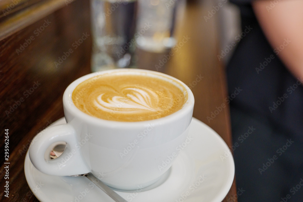 Close up and top view of beautiful latte art with heart pattern on top of coffee cappuccino in white ceramic cup on wood counter in coffee bar. Close up and top view of beautiful latte art with heart pattern on top of coffee cappuccino in white ceramic cup on wood counter in coffee bar.