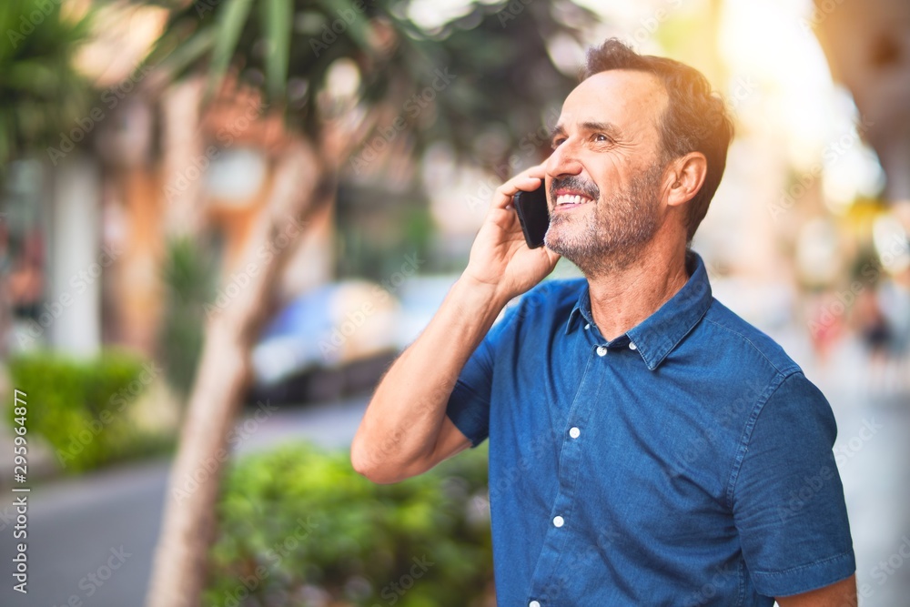 Middle age handsome businessman standing on the street talking on the smartphone smiling Middle age handsome businessman standing on the street talking on the smartphone smiling