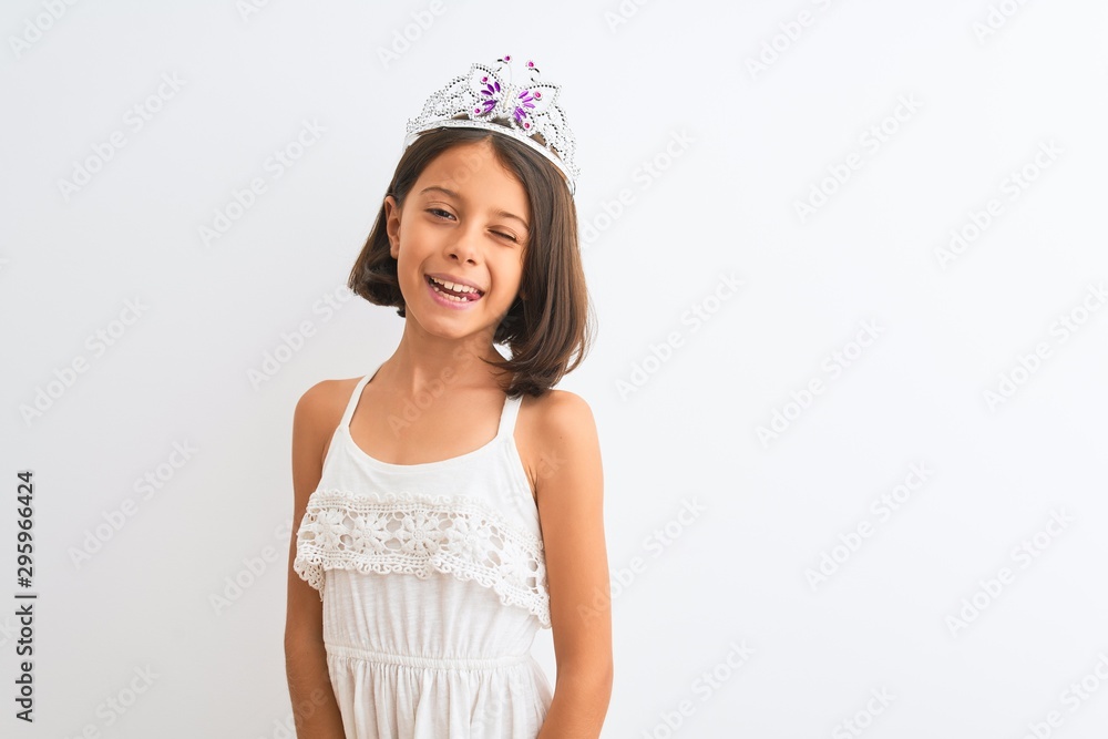 Beautiful child girl wearing princess crown standing over isolated white background winking looking at the camera with sexy expression, cheerful and happy face. Beautiful child girl wearing princess crown standing over isolated white background winking looking at the camera with sexy expression, cheerful and happy face.