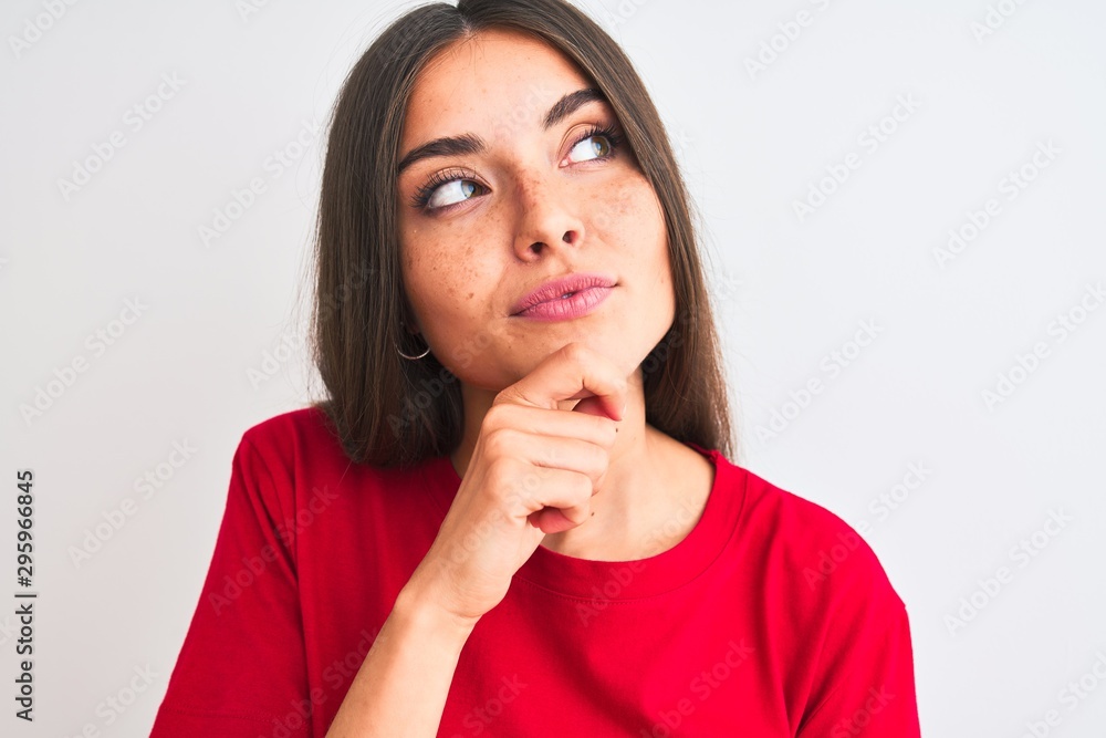 Young beautiful woman wearing red casual t-shirt standing over isolated white background serious face thinking about question, very confused idea Young beautiful woman wearing red casual t-shirt standing over isolated white background serious face thinking about question, very confused idea