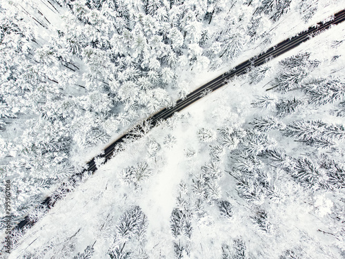 Beautiful aerial view of snow covered pine forests and a road winding among trees. Rime ice and hoar frost covering trees. Scenic winter landscape in Vilnius, Lithuania.