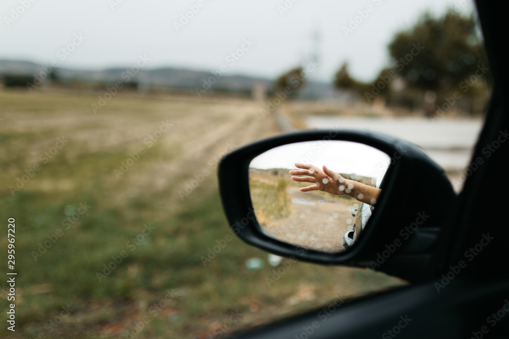 Hand touching rain drops. Mirror seen through the glass. Wet car window. Close up rain drop. Car view see the mirror. Rainy day. Hand touching rain drops. Mirror seen through the glass. Wet car window. Close up rain drop. Car view see the mirror. Rainy day.