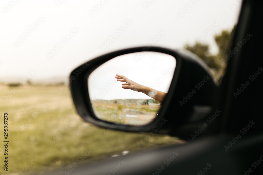 Hand touching rain drops. Mirror seen through the glass. Wet car window. Close up rain drop. Car view see the mirror. Rainy day.