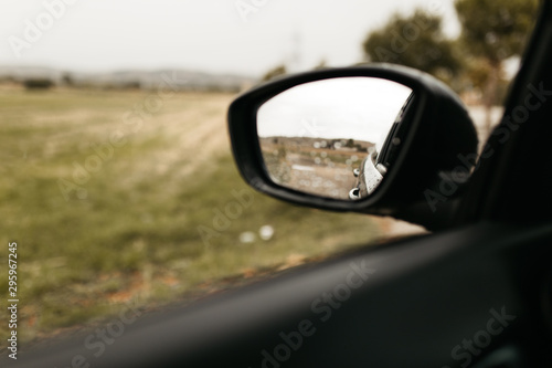 Rear view mirror seen through the glass. Wet car window. Close up rain drop. Car view see the mirror.
