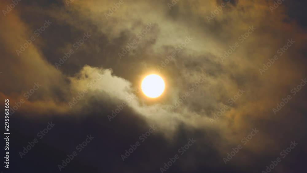 Sun rising through thick ominous clouds, sweeping quickly by. The dense clouds actually warp the shape of the sun as they pass. Sun rising through thick ominous clouds, sweeping quickly by. The dense clouds actually warp the shape of the sun as they pass.