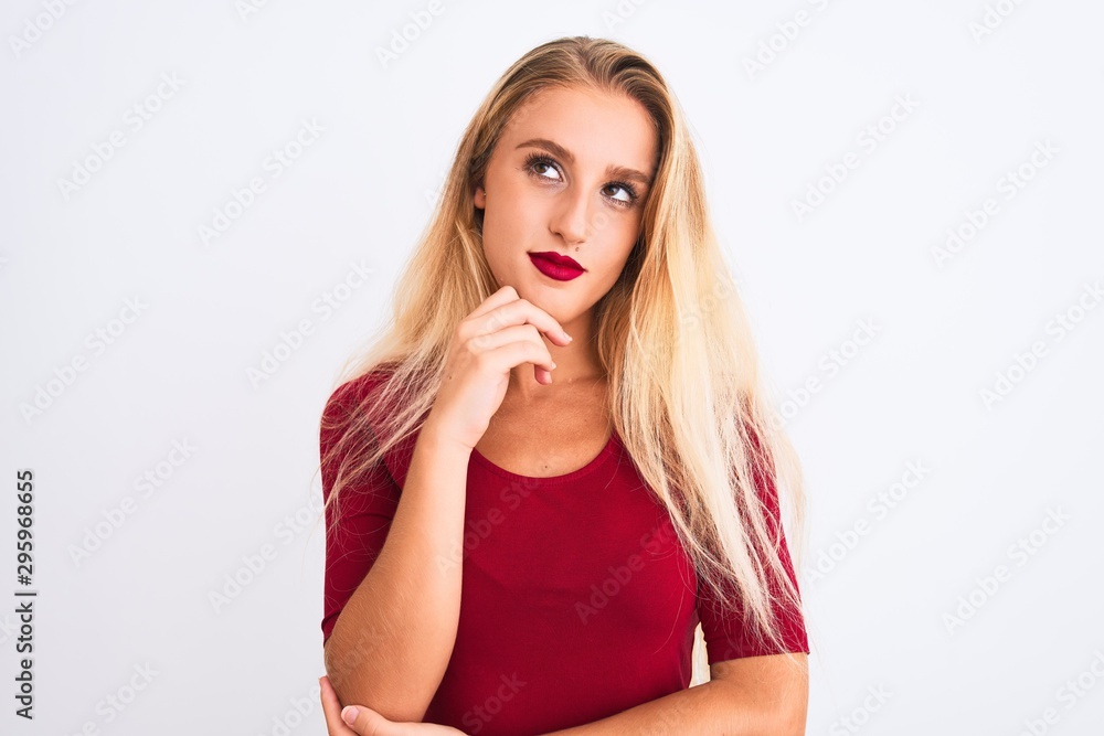 Young beautiful woman wearing red t-shirt standing over isolated white background with hand on chin thinking about question, pensive expression. Smiling with thoughtful face. Doubt concept.