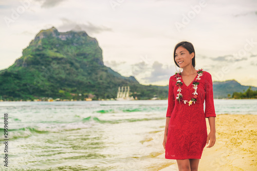 Bora Bora luxury vacation beautiful Asian tourist woman on Tahiti French Polynesia cruise ship travel adventure. Girl smiling wearing lei flower necklace on sunset beach walk.