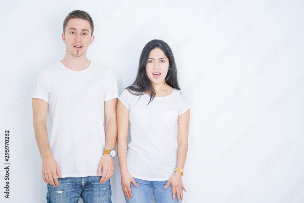 Young beautiful couple wearing casual t-shirt standing over isolated white background afraid and shocked with surprise expression, fear and excited face. Young beautiful couple wearing casual t-shirt standing over isolated white background afraid and shocked with surprise expression, fear and excited face.