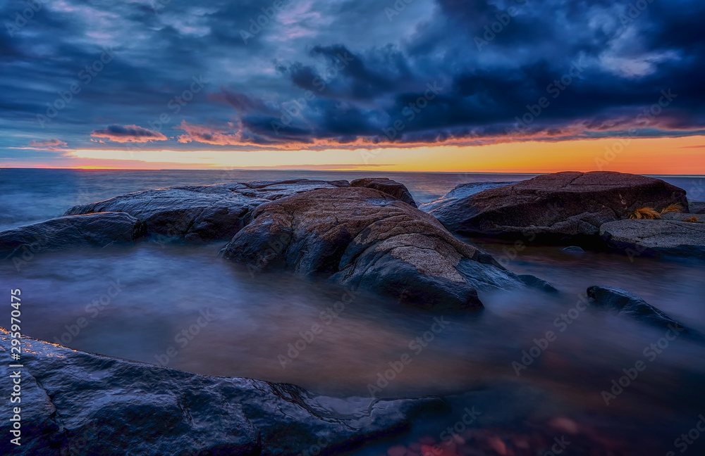Fototapeta premium Dramatic sunrise Clouds over rocks and waves