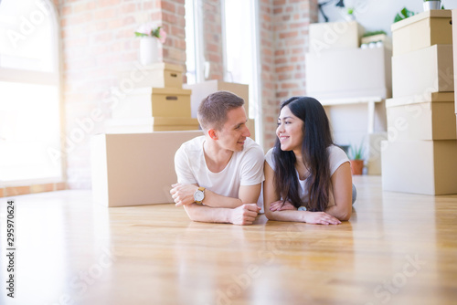 Young beautiful couple lying down at new home around cardboard boxes