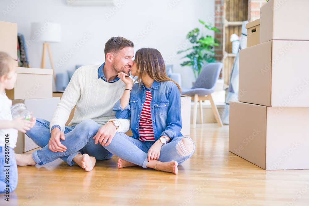 Young beautiful couple sitting on the floor kissing at new home around cardboard boxes Young beautiful couple sitting on the floor kissing at new home around cardboard boxes