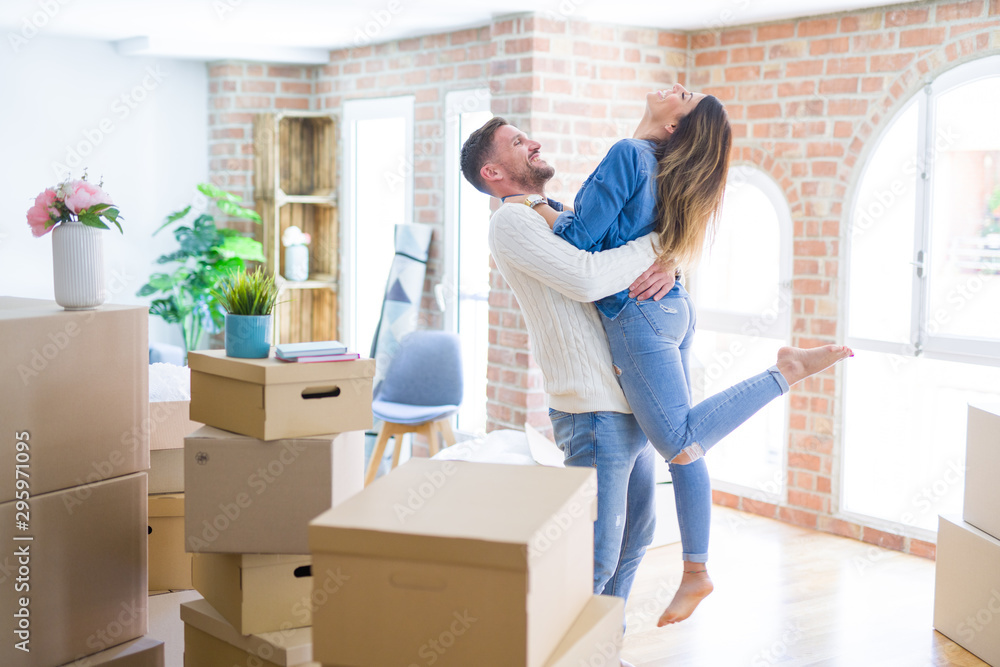 Young beautiful couple hugging at new home around cardboard boxes Young beautiful couple hugging at new home around cardboard boxes