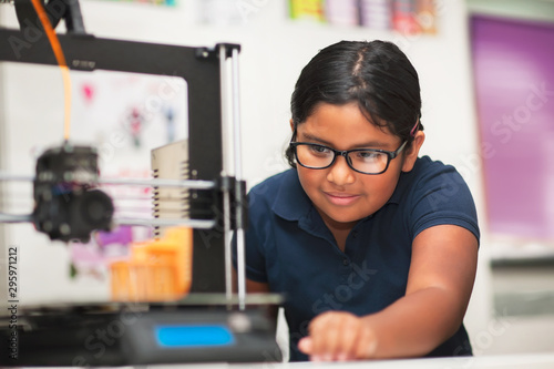 A female student in a modern classroom observing the printing process of a 3d model. photo
