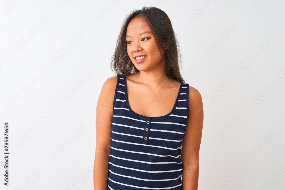 Young chinese woman wearing striped t-shirt standing over isolated white background looking away to side with smile on face, natural expression. Laughing confident. Young chinese woman wearing striped t-shirt standing over isolated white background looking away to side with smile on face, natural expression. Laughing confident.