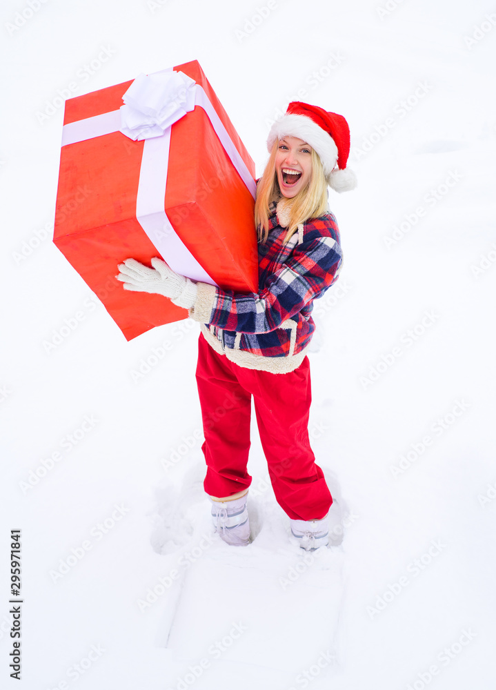 Obraz premium Big gift box. Funny woman holding a big Christmas present - full length. Happy woman in red dress having fun with big gift box isolated on a white snow background.