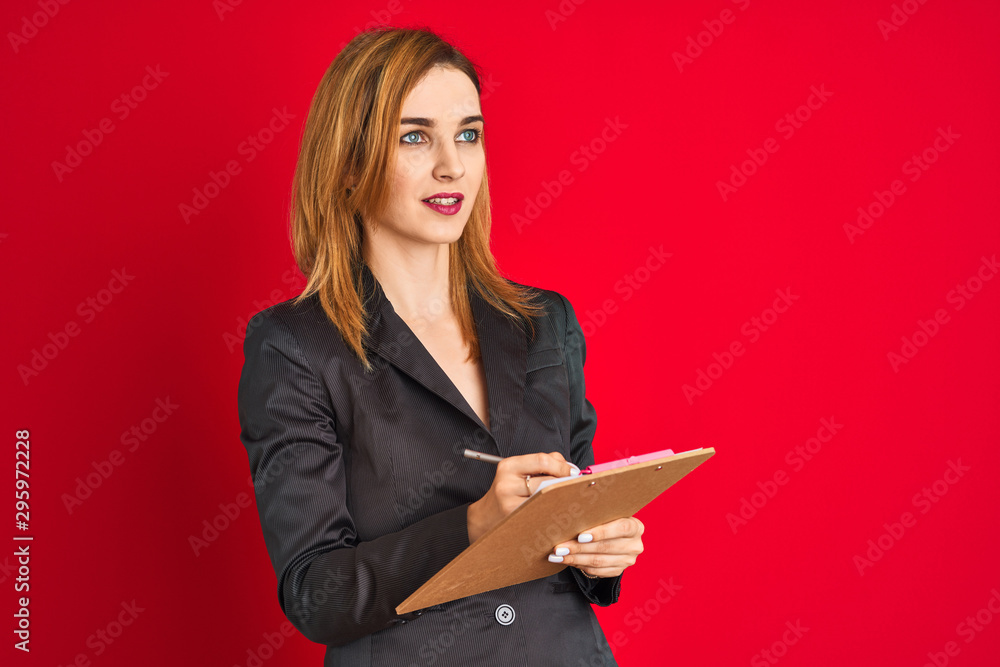 Young beautiful redhead businesswoman wearing suit writing on flip board Young beautiful redhead businesswoman wearing suit writing on flip board