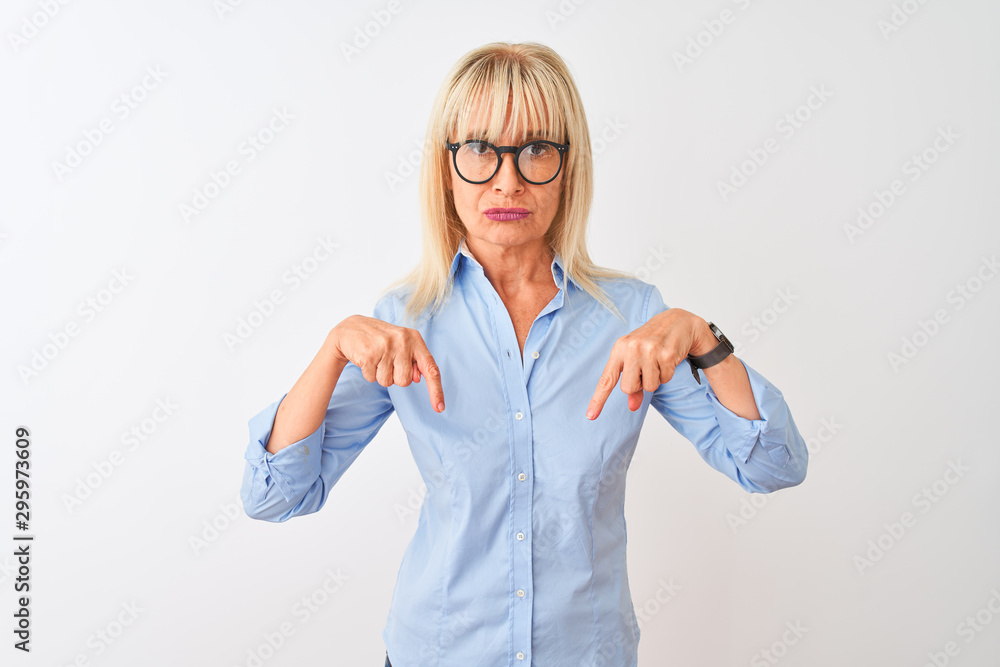Middle age businesswoman wearing elegant shirt and glasses over isolated white background Pointing down looking sad and upset, indicating direction with fingers, unhappy and depressed. Middle age businesswoman wearing elegant shirt and glasses over isolated white background Pointing down looking sad and upset, indicating direction with fingers, unhappy and depressed.