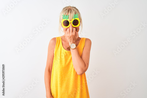 Middle age woman on vacation wearing pineapple sunglasses over isolated white background looking stressed and nervous with hands on mouth biting nails. Anxiety problem.