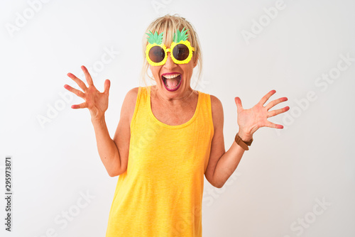 Middle age woman on vacation wearing pineapple sunglasses over isolated white background celebrating crazy and amazed for success with arms raised and open eyes screaming excited. Winner concept