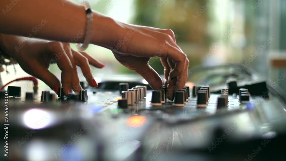 Hands of a female DJ playing dance music on a mixing controller or a turntable deck turning knobs and levers. Close up shot of hands with a shallow focus area 4K Hands of a female DJ playing dance music on a mixing controller or a turntable deck turning knobs and levers. Close up shot of hands with a shallow focus area 4K