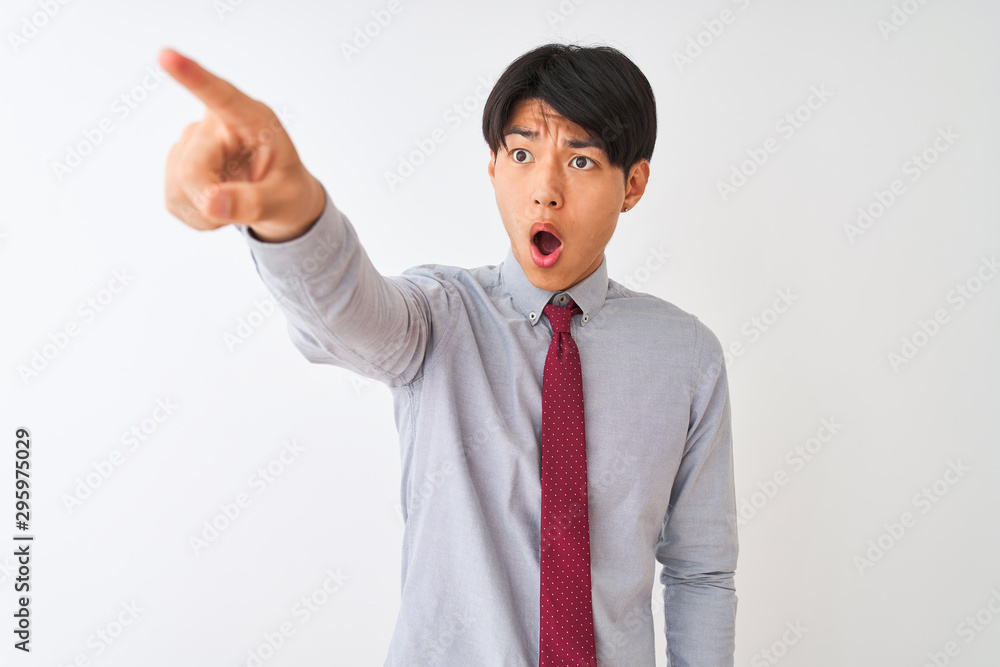 Chinese businessman wearing elegant tie standing over isolated white background Pointing with finger surprised ahead, open mouth amazed expression, something on the front Chinese businessman wearing elegant tie standing over isolated white background Pointing with finger surprised ahead, open mouth amazed expression, something on the front